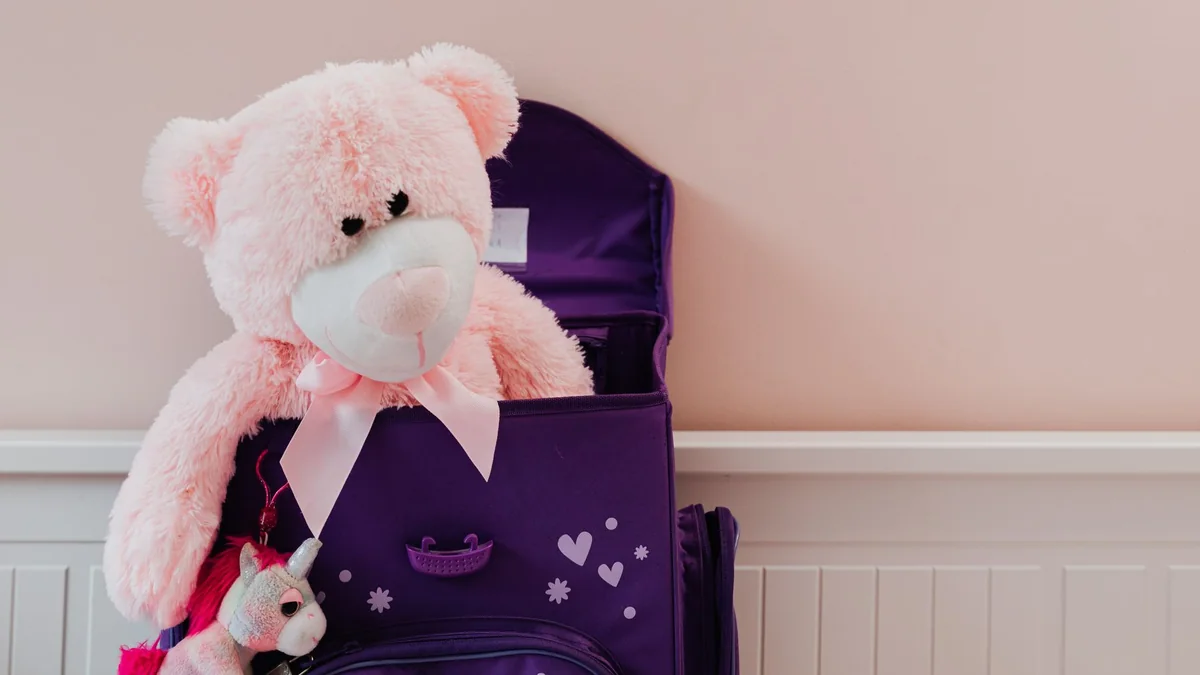Kuscheltiere neben einem gepackten Kinderkoffer